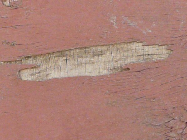 Red plywood texture made up of three chipped and cracked boards, with wood brown and grey wood visible underneath the paint.